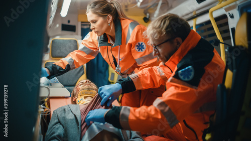 Female and Male EMS Paramedics Provide Medical Help to an Injured Patient on the Way to a Healthcare Hospital. Emergency Care Assistants Bring the Man Back to Life in an Ambulance.
