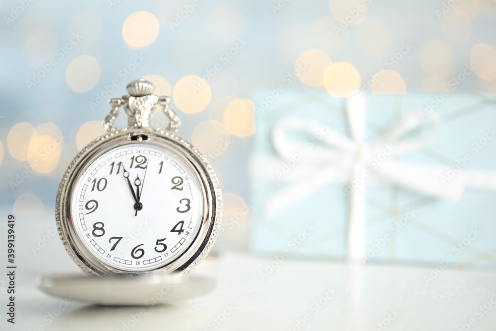Pocket watch on table against blurred lights, space for text. New Year countdown Pocket watch on table against blurred lights, space for text. New Year countdown