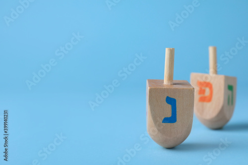 Hanukkah traditional dreidel with letter Nun on light blue background, space for text photo