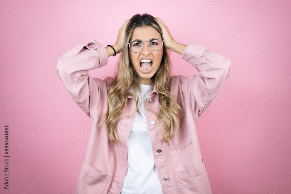 Young beautiful blonde woman with long hair standing over pink background suffering from headache desperate and stressed because pain and migraine with her hands on head Young beautiful blonde woman with long hair standing over pink background suffering from headache desperate and stressed because pain and migraine with her hands on head
