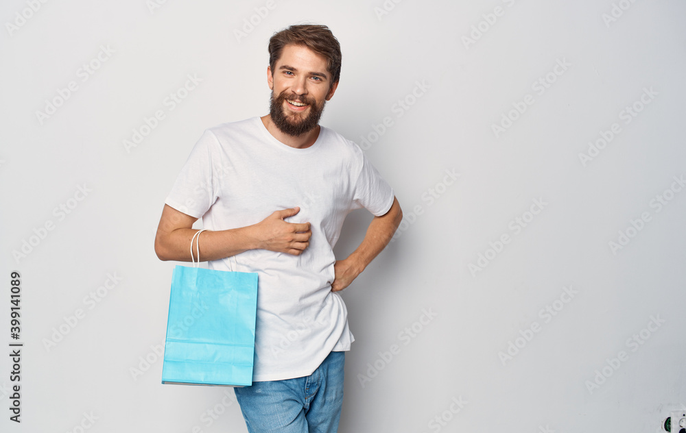 Bearded man in a white t-shirt with a package in his hand Shopping fun isolated background Bearded man in a white t-shirt with a package in his hand Shopping fun isolated background