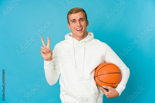 Young caucasian man playing basketball isolated on blue background © Asier