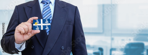 Cropped image of businessman holding plastic credit card with printed flag of Martinique. Background blurred. photo