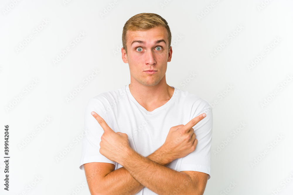 Young caucasian handsome man points sideways, is trying to choose between two options. Young caucasian handsome man points sideways, is trying to choose between two options.
