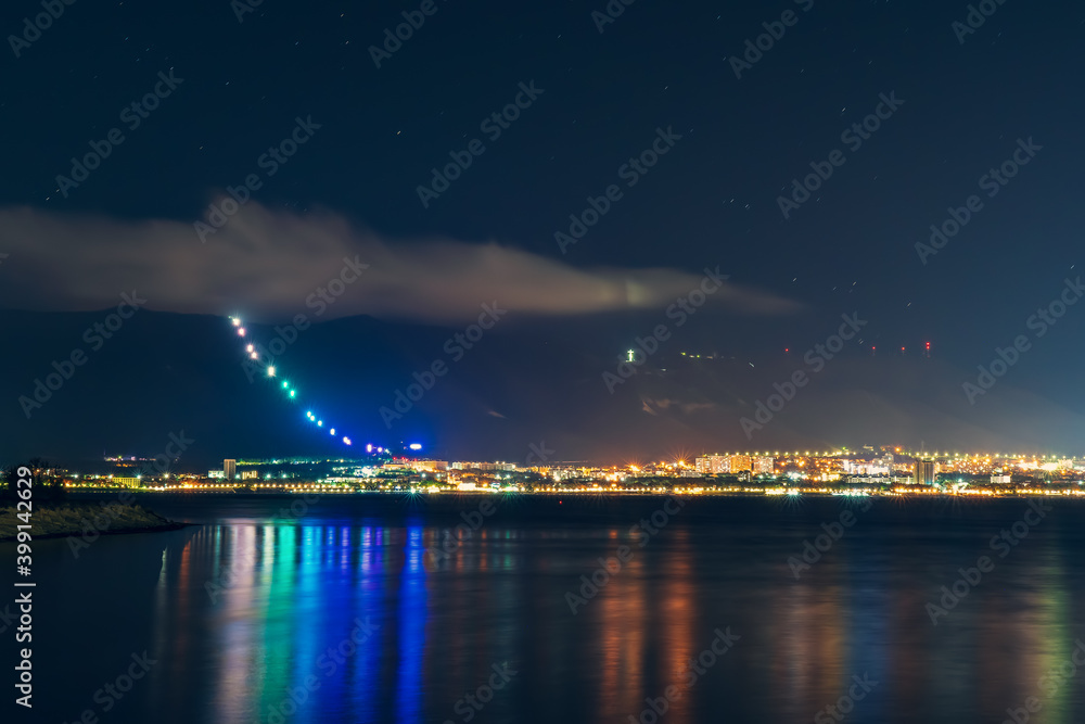 Fototapeta premium Resort city Gelendzhik with mountains and night illumination reflected in sea bay water.