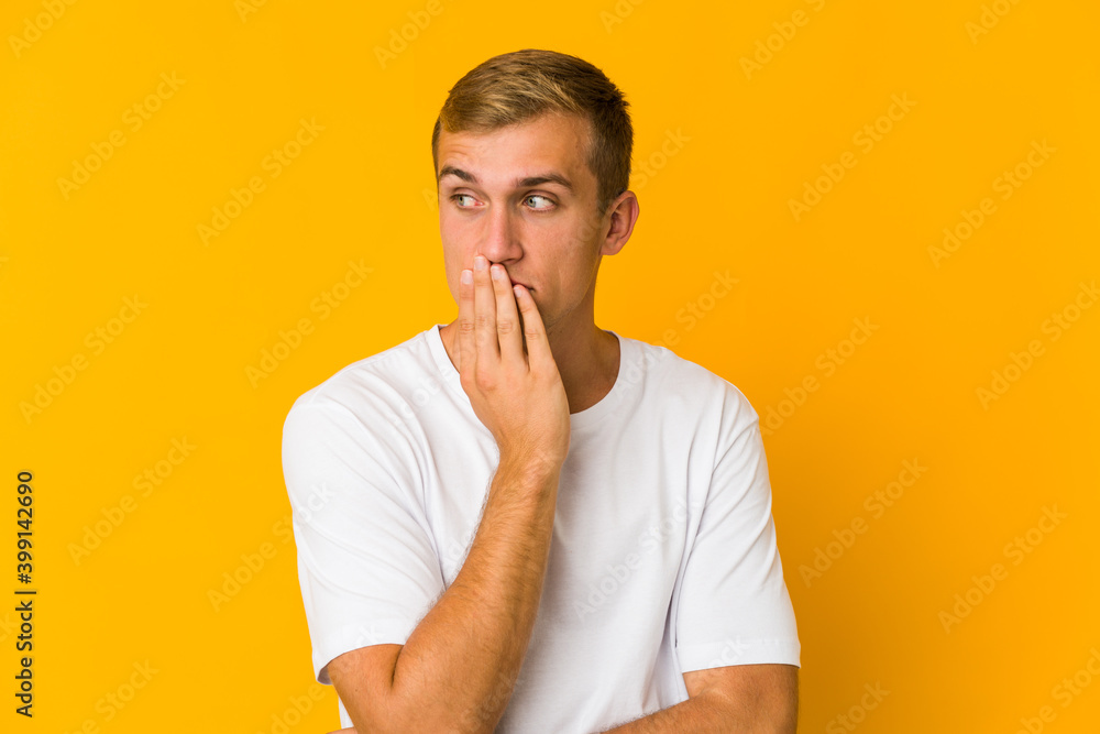 Young caucasian handsome man yawning showing a tired gesture covering mouth with hand. Young caucasian handsome man yawning showing a tired gesture covering mouth with hand.
