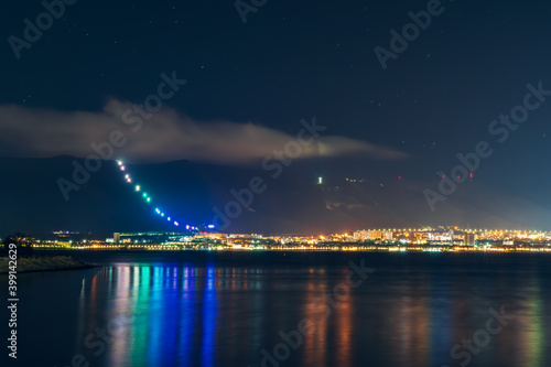 Resort city Gelendzhik with mountains and night illumination reflected in sea bay water. © DedMityay