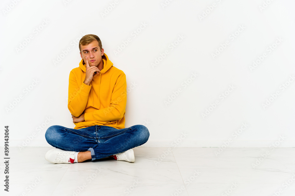 Young caucasian man sitting on the floor contemplating, planning a strategy, thinking about the way of a business.