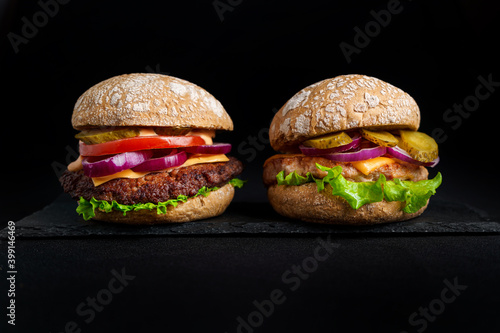 Two Burgers with meat on black plate at black background