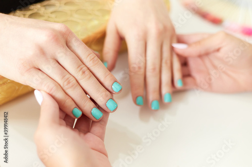 Latin manicurist doing manicure to female customer in beauty salon  presenting the finished work. Manicure and beauty salon pandemic concept.