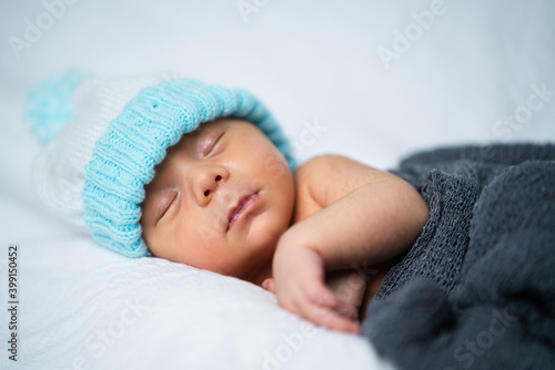 newborn baby boy with wool hat sleeping on soft white surface