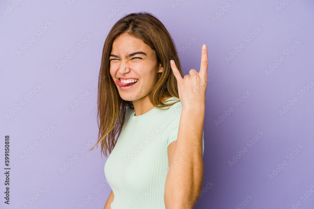 Young skinny caucasian girl teenager on purple background showing rock gesture with fingers Young skinny caucasian girl teenager on purple background showing rock gesture with fingers
