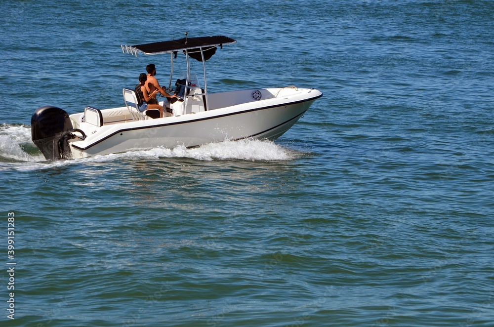 Fototapeta premium Young couple cruising on the Florida Intra-Coastal Waterway in a small open white sport fishing boat.