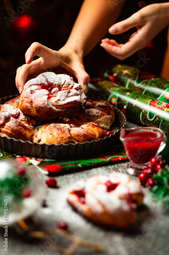 Tasty homemade braided bun with cranberry jam and sugar powder. Christmas and New Year decorations. Bokeh lights background. Vertical orientation