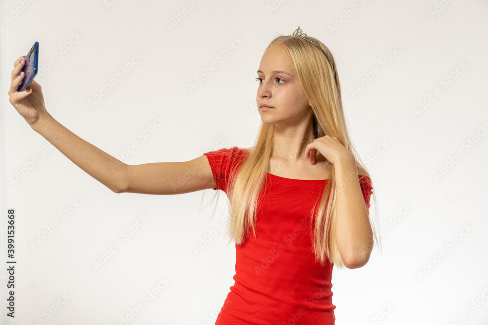 Teenage girl with blond hair in red dress holds phone Teenage girl with blond hair in red dress holds phone