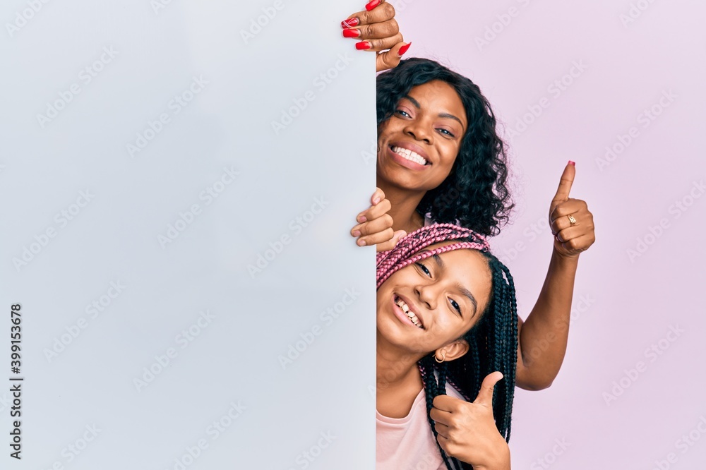 © Krakenimages.com - Beautiful african american mother and daughter holding blank empty banner smiling happy and positive, thumb up doing excellent and approval sign © Krakenimages.com - Beautiful african american mother and daughter holding blank empty banner smiling happy and positive, thumb up doing excellent and approval sign