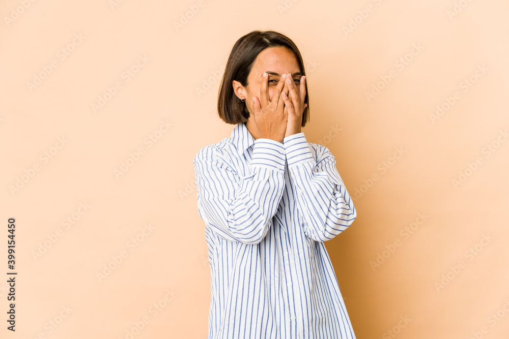 Young hispanic woman isolated blink at the camera through fingers, embarrassed covering face. Young hispanic woman isolated blink at the camera through fingers, embarrassed covering face.