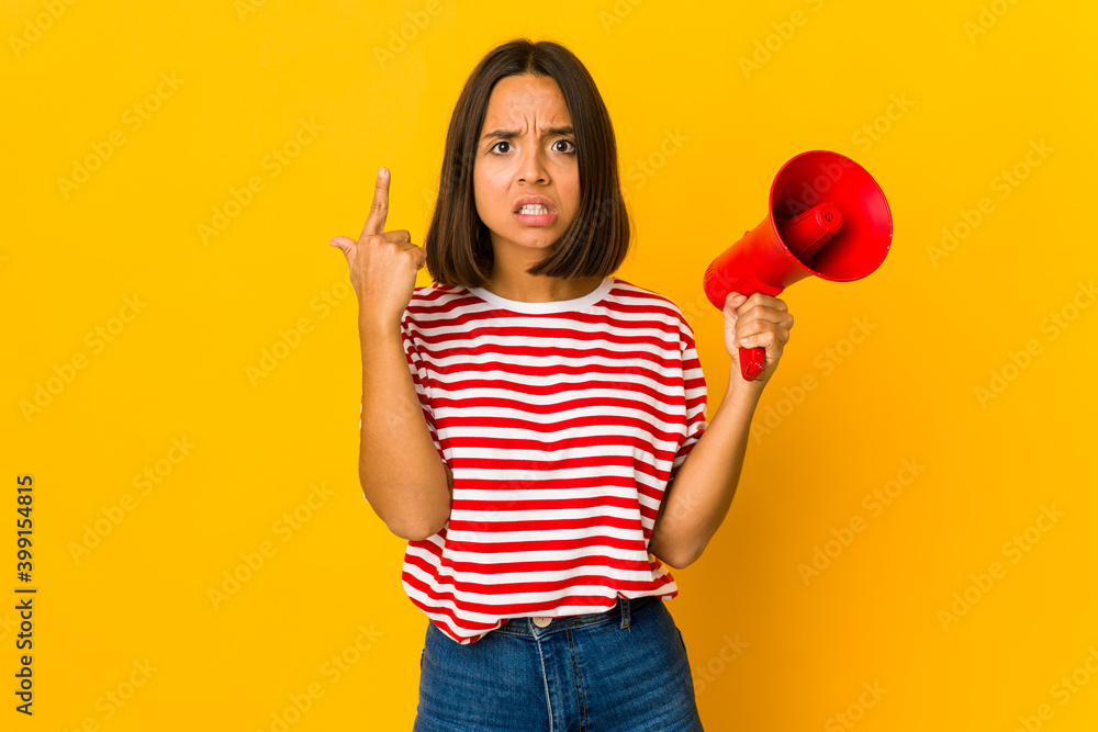 Young hispanic woman holding a megaphone showing a disappointment gesture with forefinger. Young hispanic woman holding a megaphone showing a disappointment gesture with forefinger.