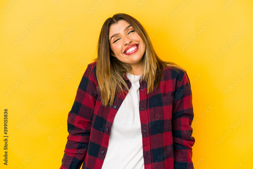 Young indian woman isolated on yellow background laughs and closes eyes, feels relaxed and happy. Young indian woman isolated on yellow background laughs and closes eyes, feels relaxed and happy.