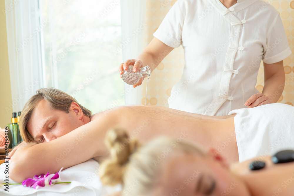 Handsome Caucasian man lying on spa bed get back massage treatment with aroma essential oil skincare from professional massage therapist at beauty salon. Wellness body massage and spa concept Handsome Caucasian man lying on spa bed get back massage treatment with aroma essential oil skincare from professional massage therapist at beauty salon. Wellness body massage and spa concept