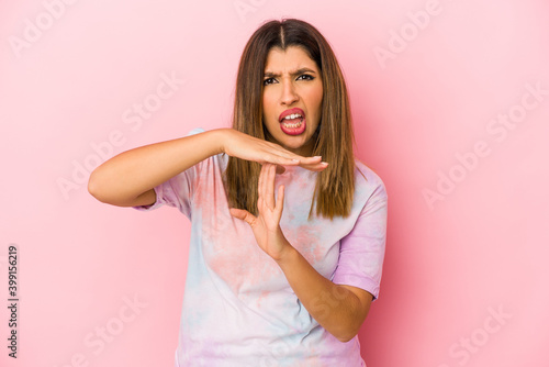 Young indian woman isolated on pink background showing a timeout gesture.