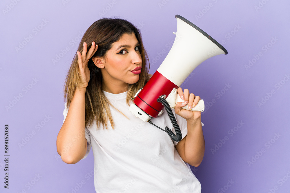 Young indian woman holding a megaphone isolated trying to listening a gossip. Young indian woman holding a megaphone isolated trying to listening a gossip.