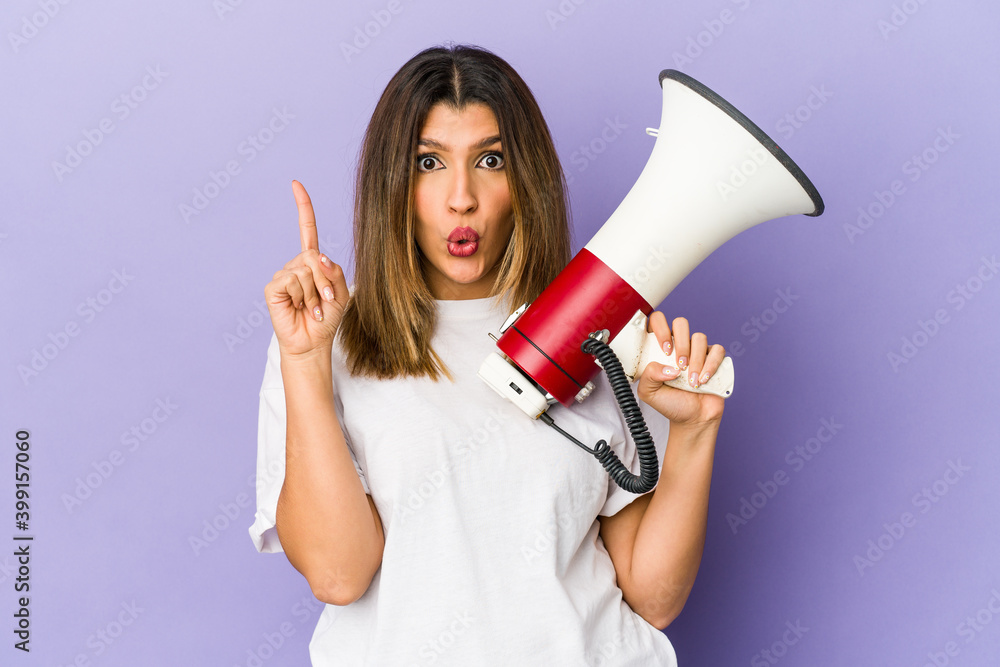 Young indian woman holding a megaphone isolated having some great idea, concept of creativity. Young indian woman holding a megaphone isolated having some great idea, concept of creativity.