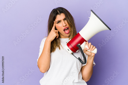 Young indian woman holding a megaphone isolated showing a disappointment gesture with forefinger.