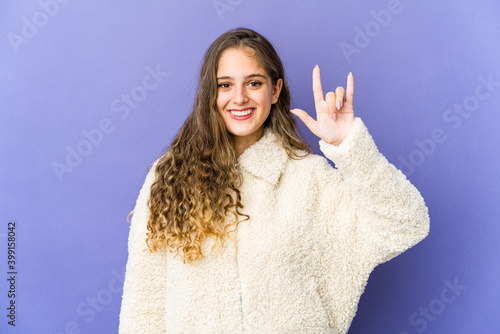 Young caucasian cute woman showing a horns gesture as a revolution concept.