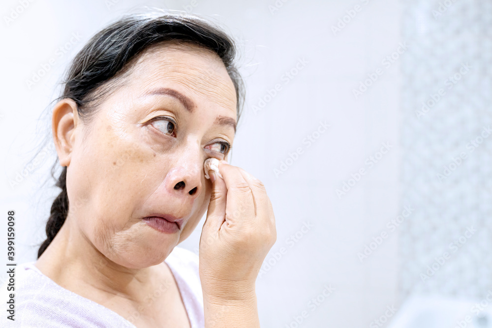 Elderly woman cleaning her face with cotton pads