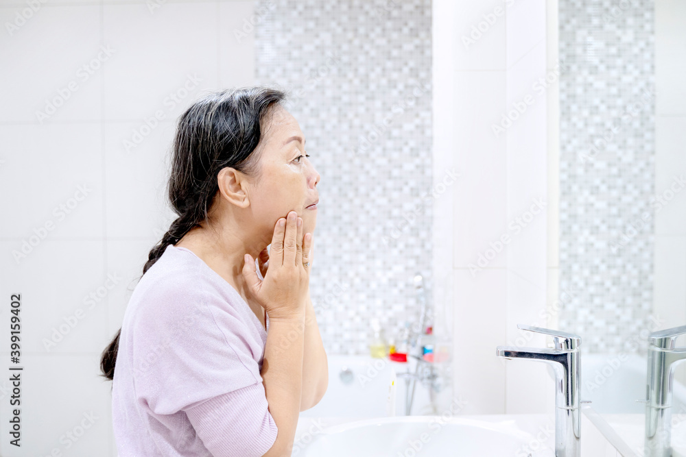Senior woman doing treatment her face skin at home Senior woman doing treatment her face skin at home