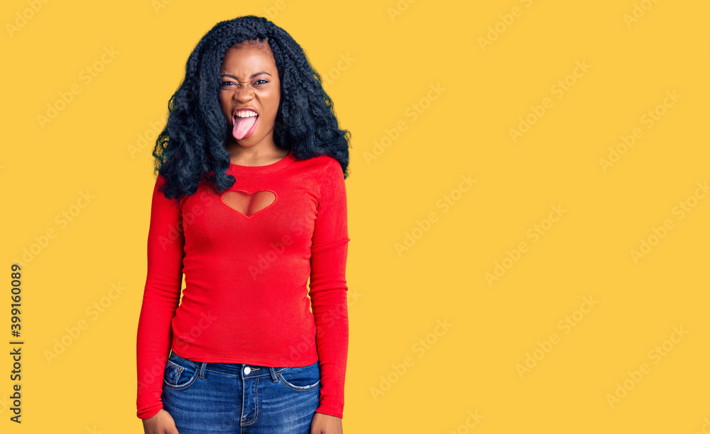 Beautiful african american woman wearing casual clothes sticking tongue out happy with funny expression. emotion concept. Beautiful african american woman wearing casual clothes sticking tongue out happy with funny expression. emotion concept.