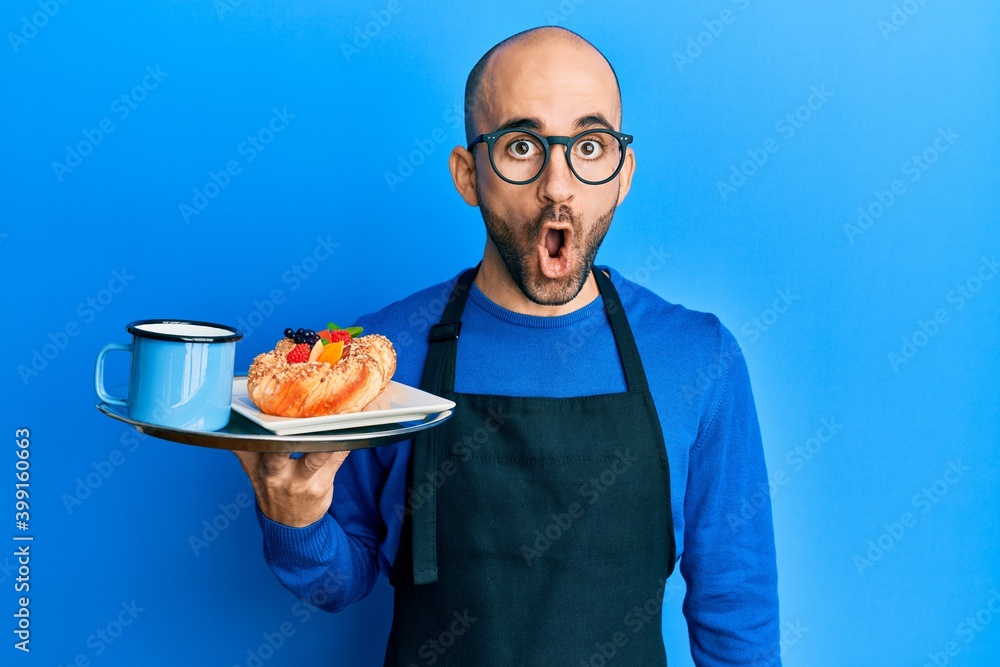 Young hispanic man wearing waiter apron holding tray with breakfast scared and amazed with open mouth for surprise, disbelief face Young hispanic man wearing waiter apron holding tray with breakfast scared and amazed with open mouth for surprise, disbelief face