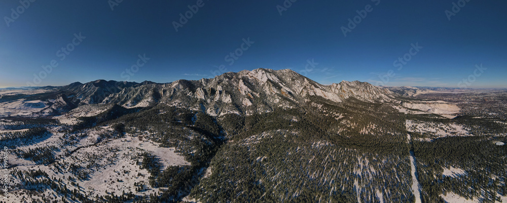 Obraz premium Snow capped foothill mountains panorama with blue sky and pine trees in Colorado