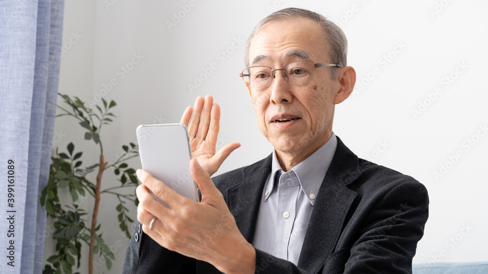 スマートフォンでテレビ電話をするシニア男性 スマートフォンでテレビ電話をするシニア男性