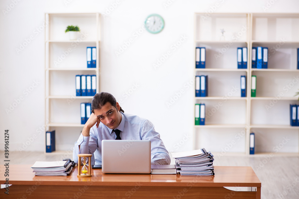 Young male employee in time management concept Young male employee in time management concept