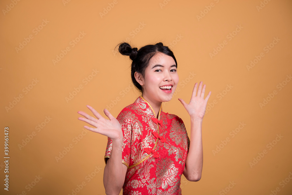 Beautiful woman wearing cheongsam and smiling at you in chinese new year on yellow background Beautiful woman wearing cheongsam and smiling at you in chinese new year on yellow background