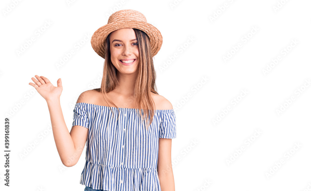 Young beautiful girl wearing hat and t shirt smiling cheerful presenting and pointing with palm of hand looking at the camera. Young beautiful girl wearing hat and t shirt smiling cheerful presenting and pointing with palm of hand looking at the camera.