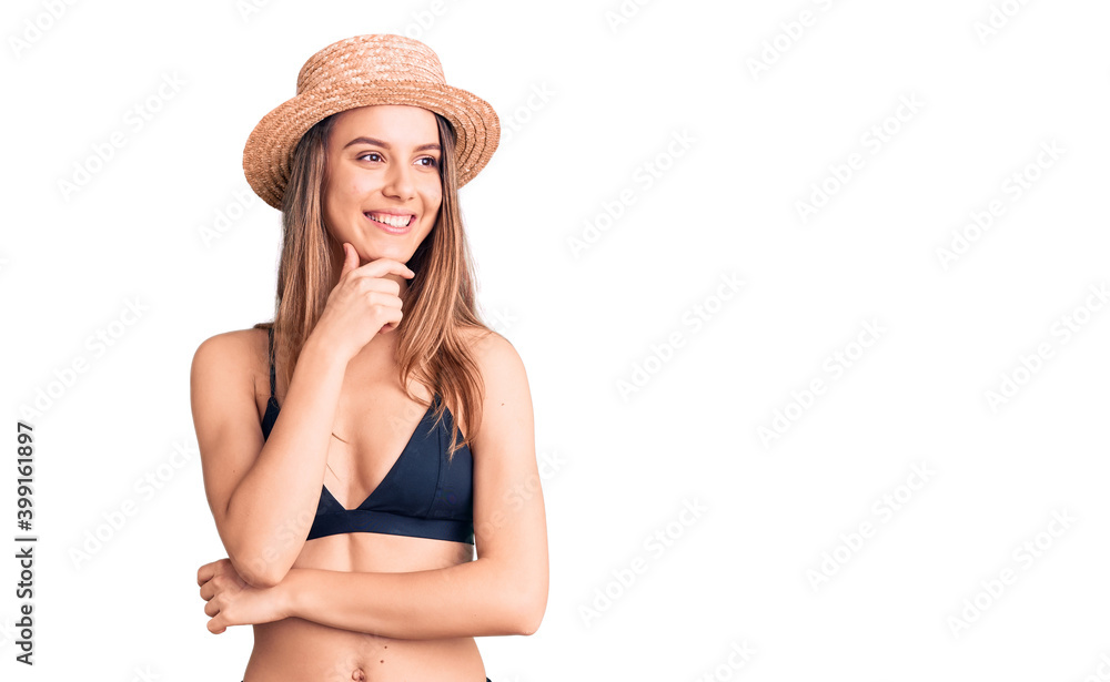 Young beautiful girl wearing bikini and hat with hand on chin thinking about question, pensive expression. smiling with thoughtful face. doubt concept. Young beautiful girl wearing bikini and hat with hand on chin thinking about question, pensive expression. smiling with thoughtful face. doubt concept.