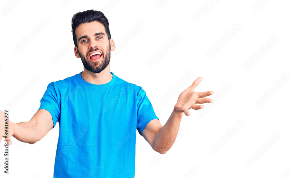 Young handsome man with beard wearing casual t-shirt smiling cheerful offering hands giving assistance and acceptance. Young handsome man with beard wearing casual t-shirt smiling cheerful offering hands giving assistance and acceptance.