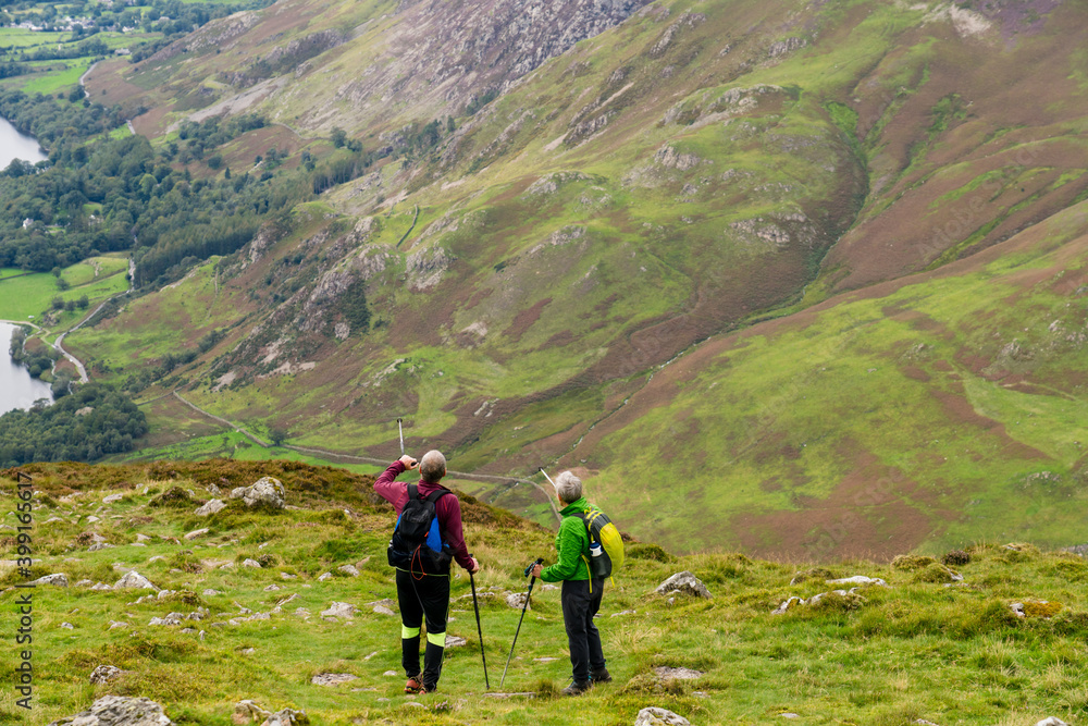 Senior hikers in Lake District looking at Buttermere lake from Haystacks peak