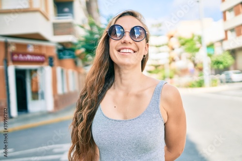 Young blonde woman smiling happy walking at street of city