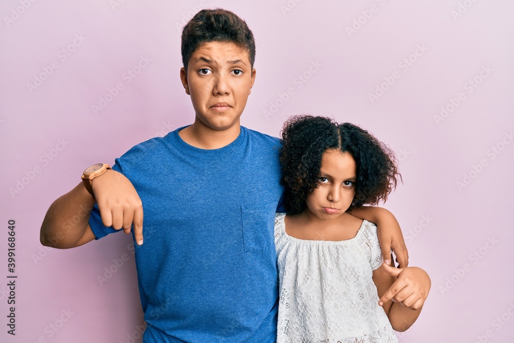 Young hispanic family of brother and sister wearing casual clothes together pointing down looking sad and upset, indicating direction with fingers, unhappy and depressed. Young hispanic family of brother and sister wearing casual clothes together pointing down looking sad and upset, indicating direction with fingers, unhappy and depressed.