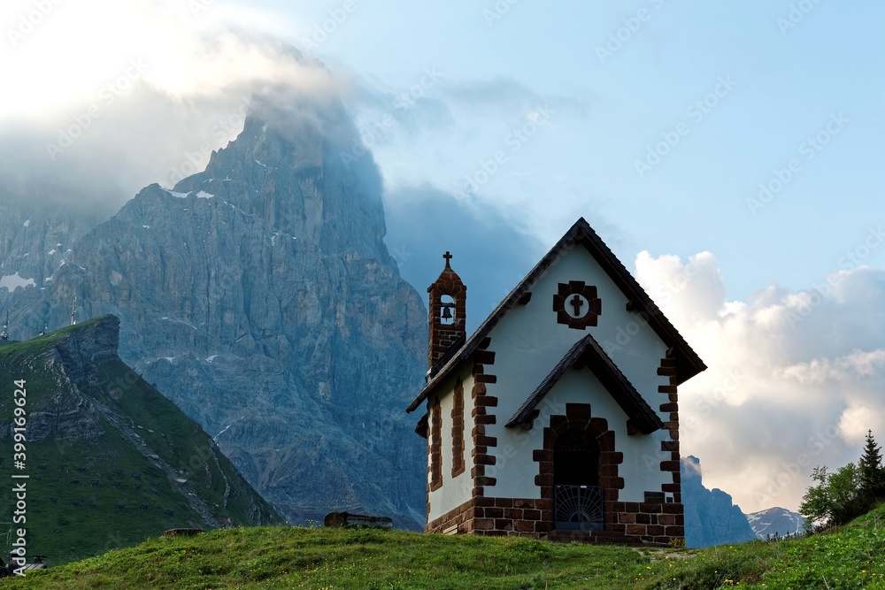 Morning scenery of a lovely chapel at the foothills of rugged mountain peaks ( Cimon della Pala ) under dramatic dawning sky in Passo Rolle, Dolomiti, Trentino Alto Adige, South Tyrol, Italy, Europe