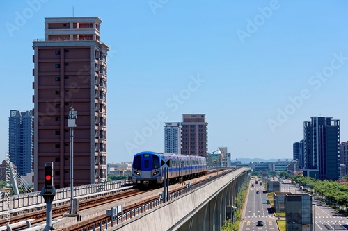 Scenic view of a metro train traveling on elevated rails of Taoyuan Mass Rapid Transit System (Taoyuan International Airport MRT System) under sunny blue sky in Chunli, New Taipei City, Taiwan