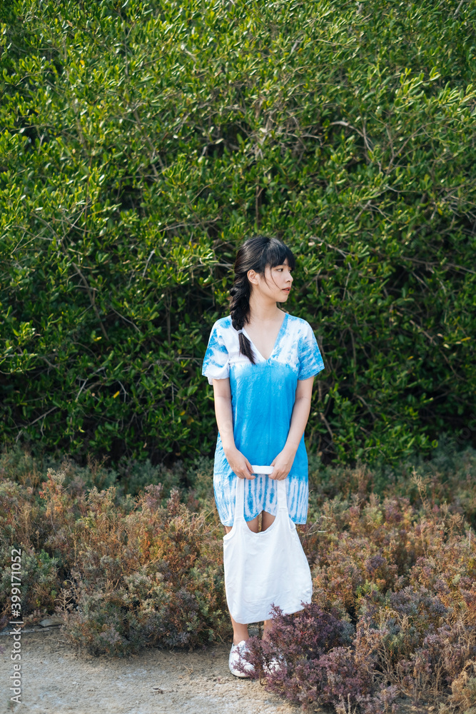 Asian woman wear blue dress with white canvas bag in nature. Asian woman wear blue dress with white canvas bag in nature.