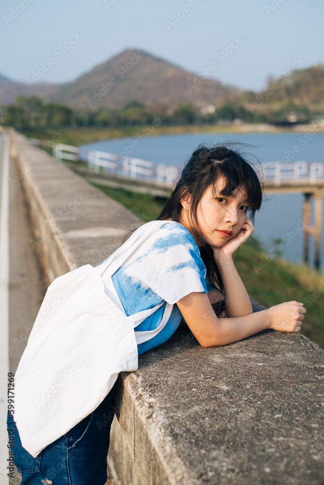 Asian woman wear blue dress with white canvas at barricade at the dam. Asian woman wear blue dress with white canvas at barricade at the dam.