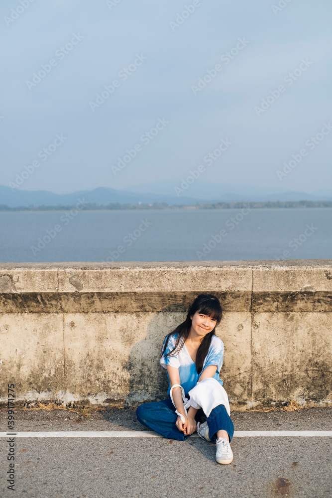 Asian woman wear blue dress with white canvas sitting on dam road. Asian woman wear blue dress with white canvas sitting on dam road.