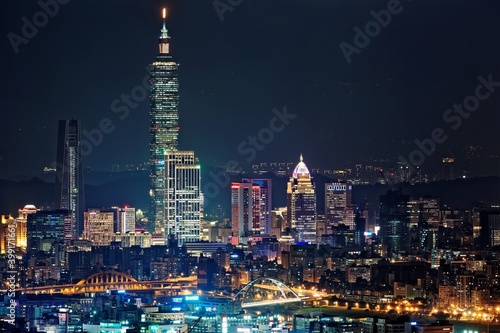 Night scenery of Downtown Taipei, the vibrant capital city of Taiwan, with view of Taipei 101 Tower standing among high-rise buildings in Xinyi Financial District and city lights dazzling in the dark