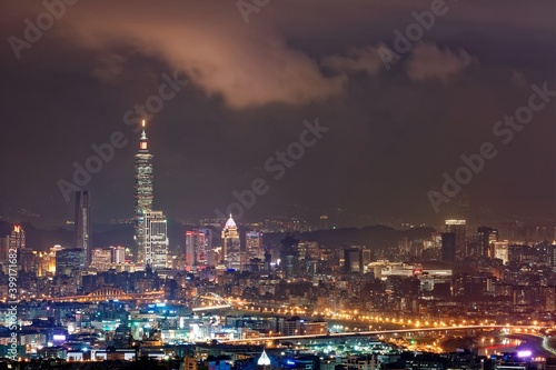 Night scenery of Downtown Taipei  the vibrant capital city of Taiwan  with view of Taipei 101 Tower standing among high-rise buildings in Xinyi Financial District and city lights dazzling in the dark